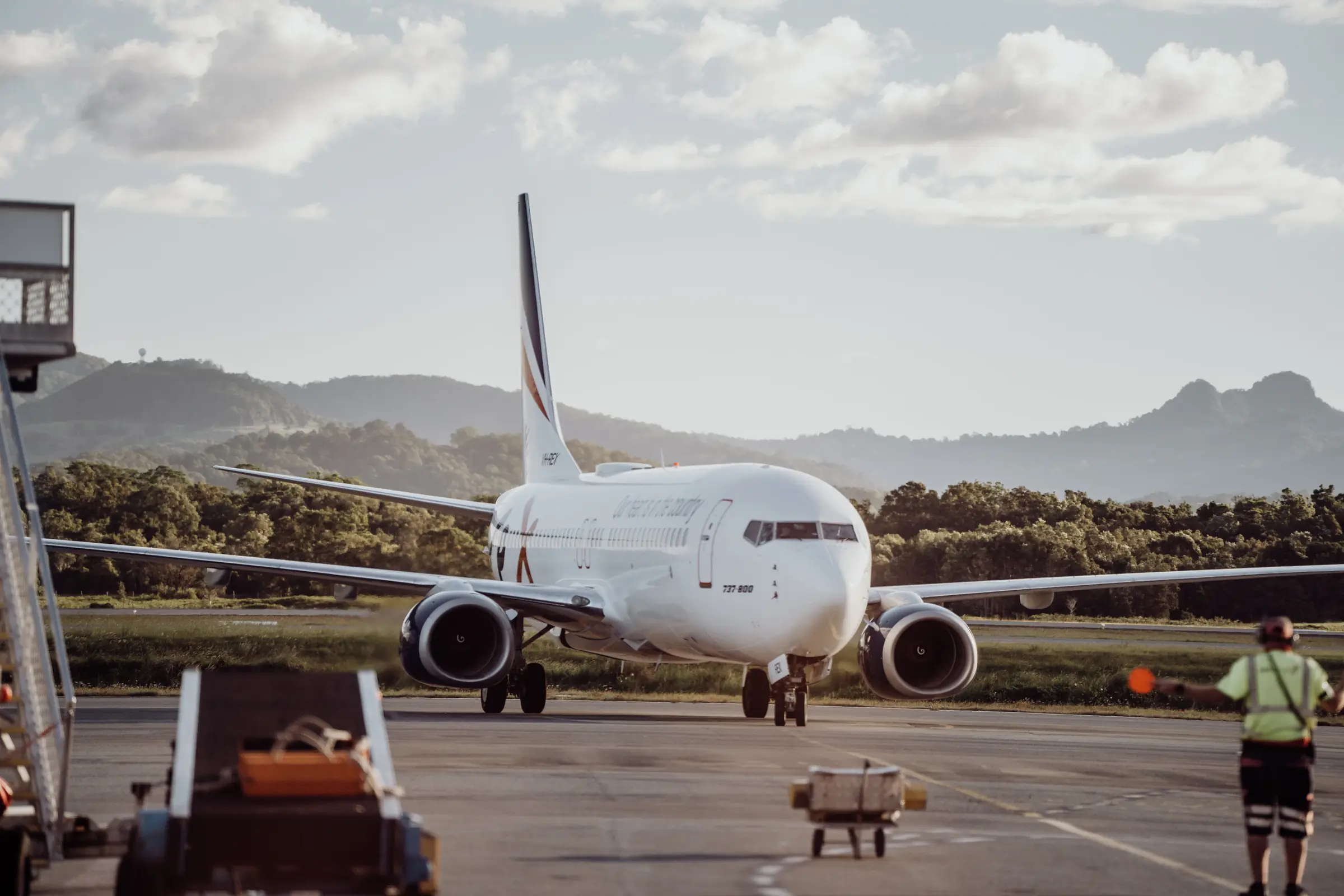 Commercial aircraft on the airport tarmac with ground crew operations nearby