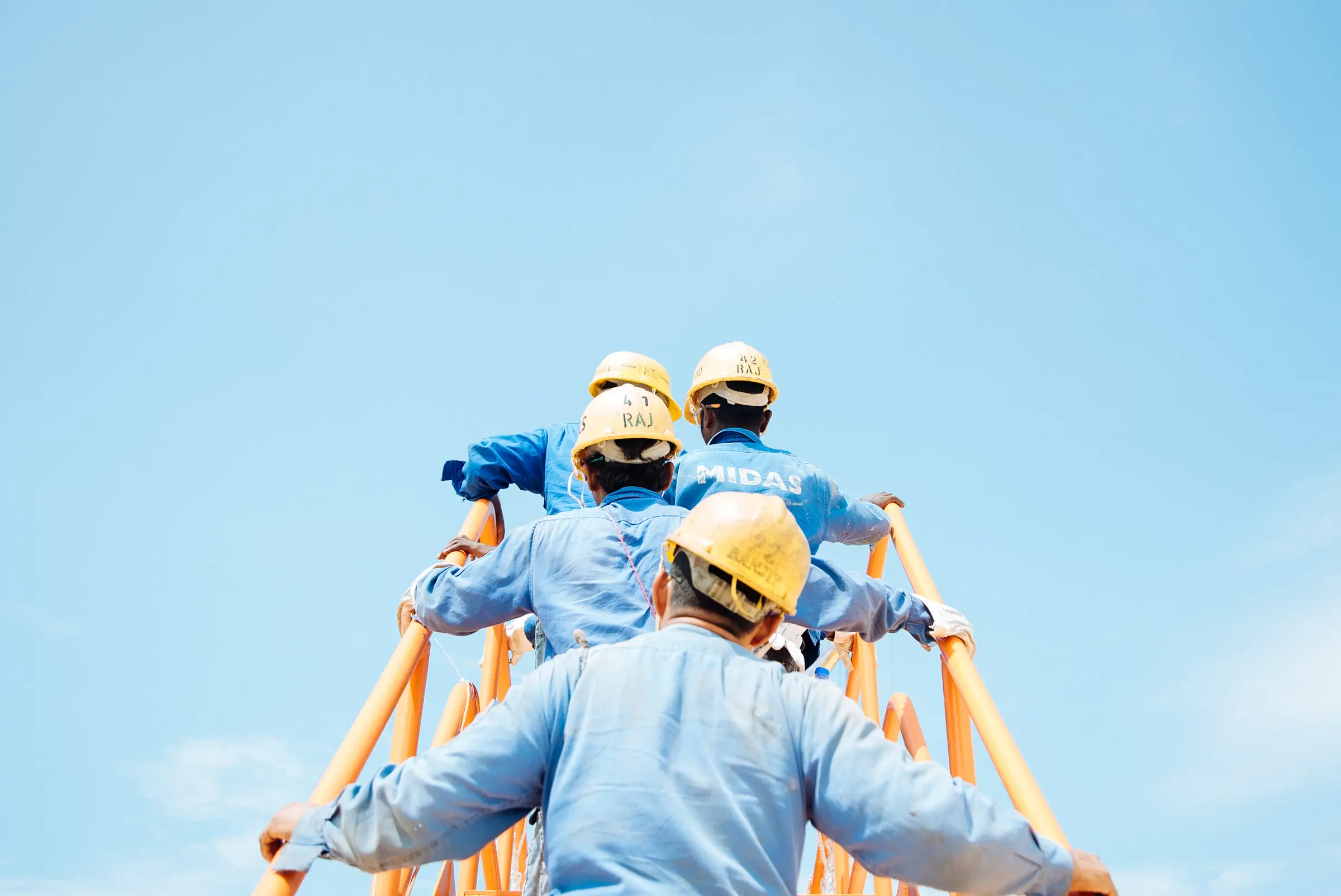 Construction workers moving up a stairwell in high-visibility PPE on an active work site