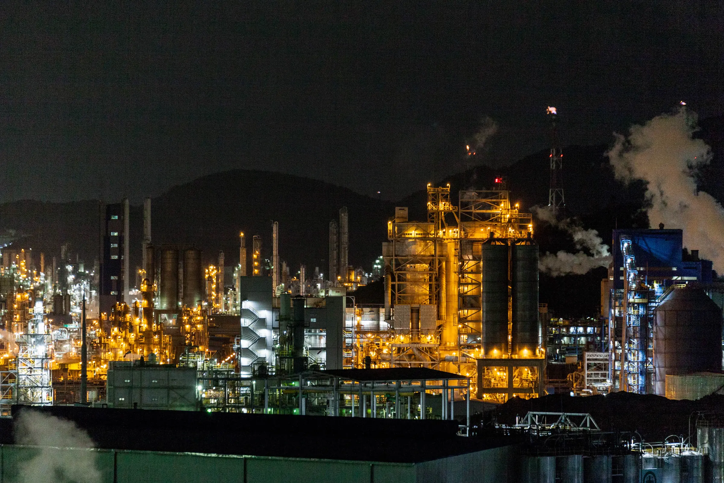 Industrial manufacturing facility exterior at night with illuminated production buildings